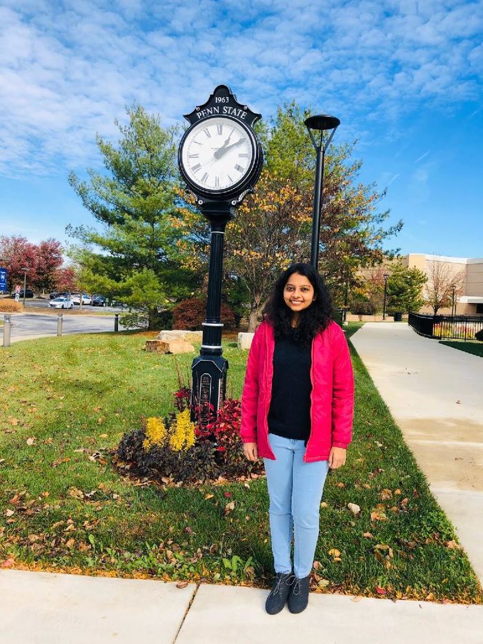 Shanmugapriya Viswanathan stands in front of the outdoor clock at Penn State Great Valley