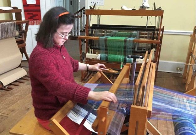 A woman working on a a project at a loom