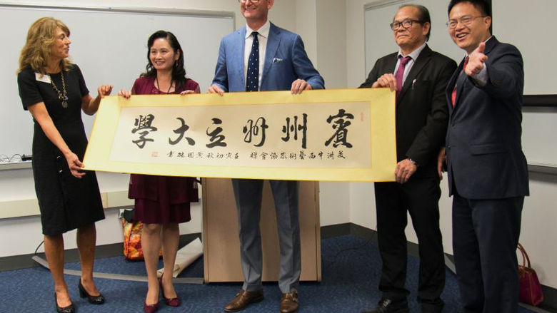 Five people holding a calligraphy artwork
