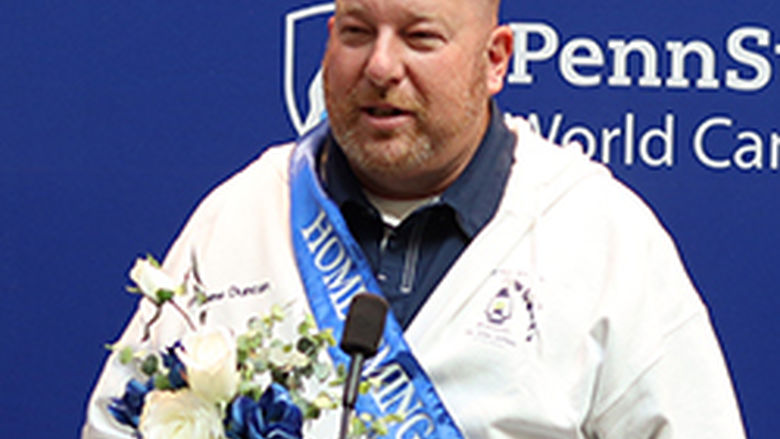 A man stands at a podium in front of a blue background.