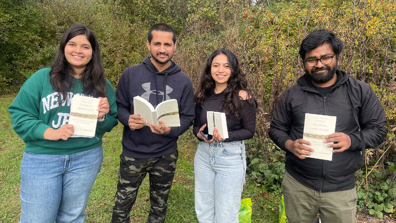 Four students holding books outside