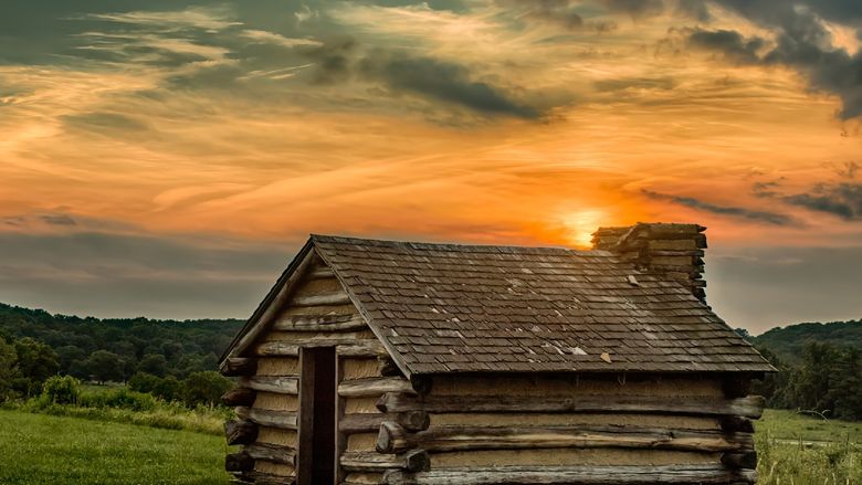 Sun setting over a wood cabin
