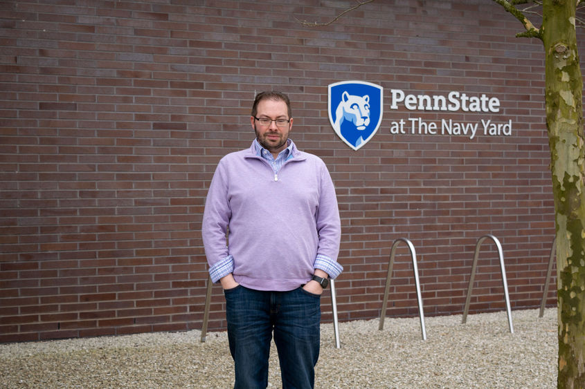 Todd Krout standing in front of the Penn State at the Navy Yard logo on Build 7R at the Navy Yard