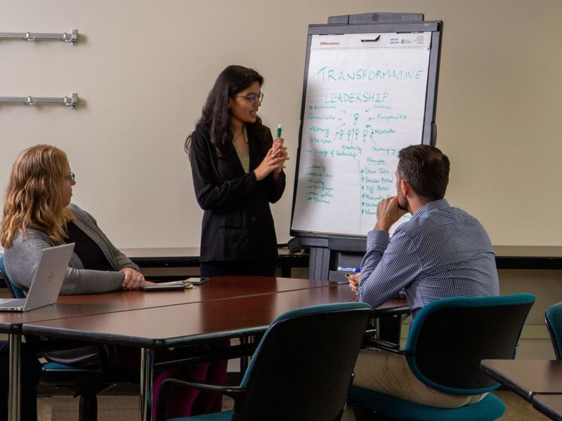 A businesswoman presents about transformative leadership to two colleagues