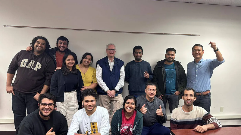 A group of students and a professor smiling in a classroom