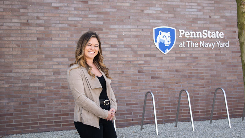 Alexis Doherty standing in front of a wall with the Penn State at the Navy Yard logo