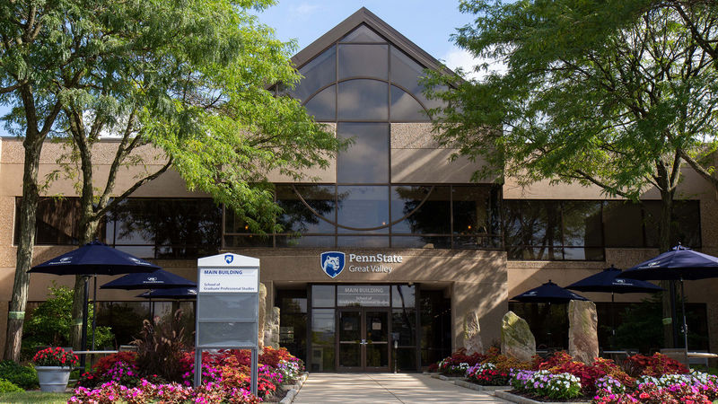 The exterior of the Main Building, framed by trees and flowers