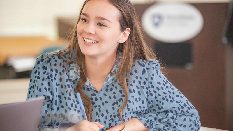 Smiling woman taking notes in a classroom