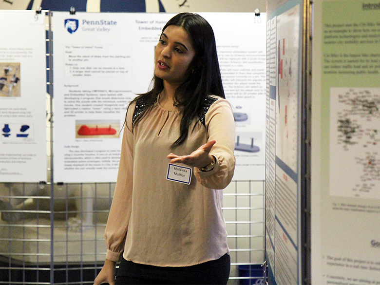 A female student talks in front of posters displayed in a lobby