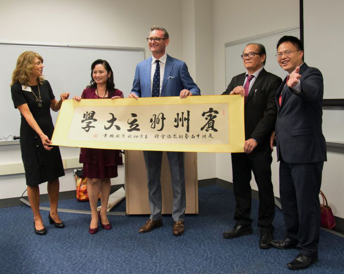 Five people holding a calligraphy artwork