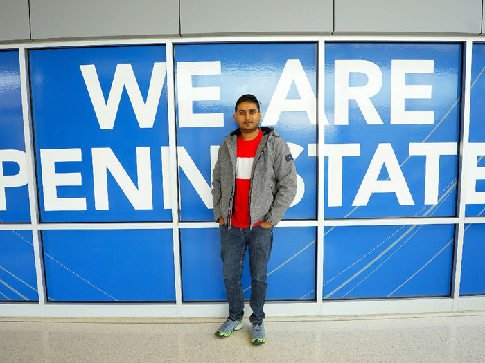 person standing in front of we are penn state sign