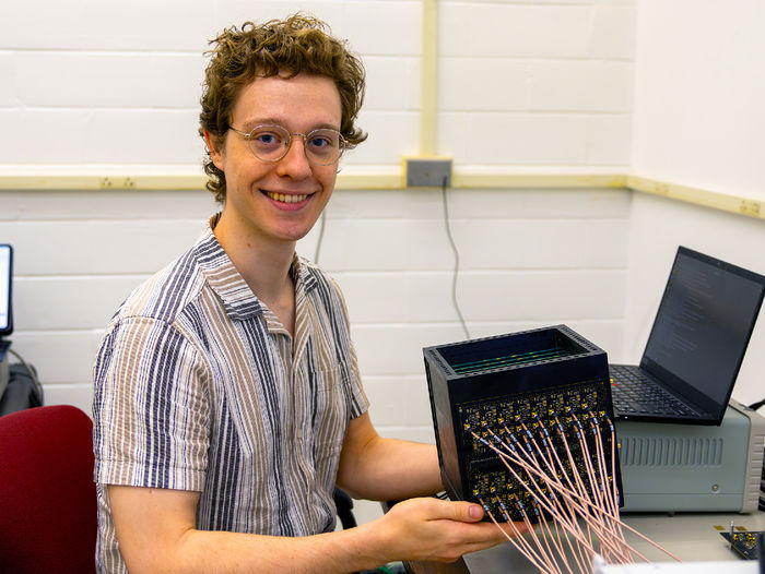 person at computer desk next to scientific device