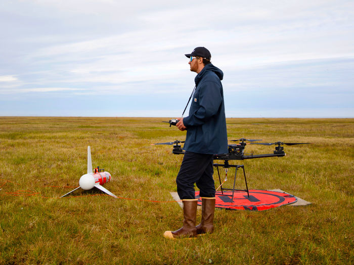 person standing next to drones in field