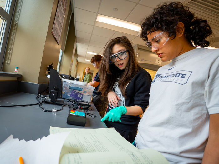 two people at desk pointing at papers and electronic device