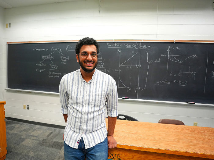 person standing in front of chalkboard with equations on it