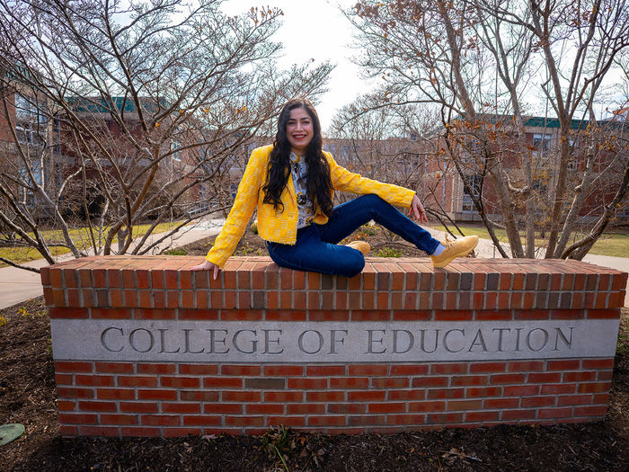 woman sitting on College of Education sign