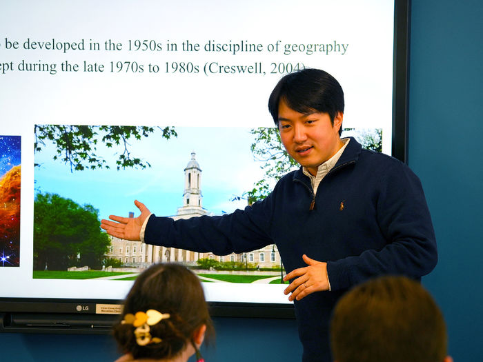 person pointing to projector screen while giving a lecture