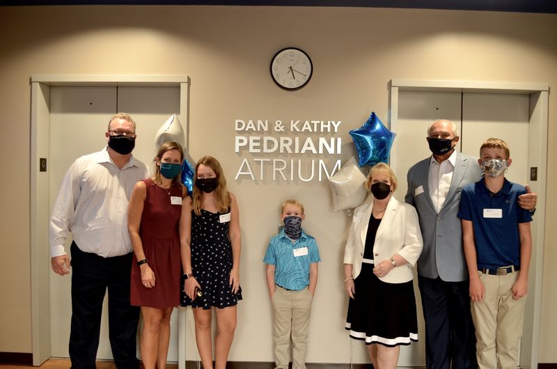 The Pedriani family standing in front of a wall that says "Dan & Kathy Pedriani Atrium"