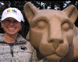 A woman poses next to the Nittany Lion Shrine.