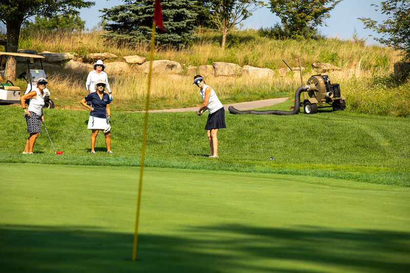 A woman hits a golf ball while 3 other women watch