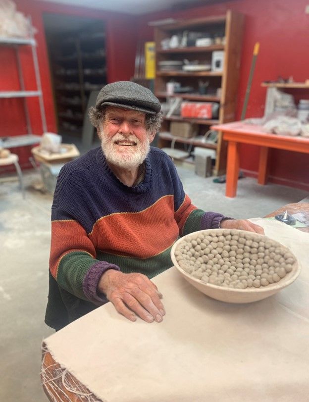 A man smiling by a ceramic bowl
