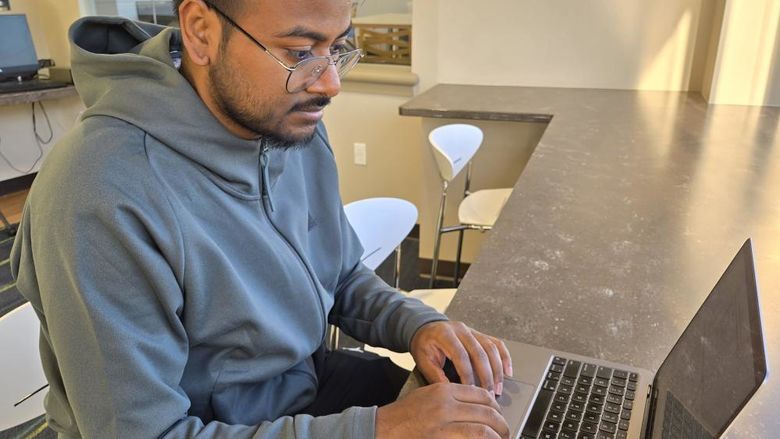 A student researcher works on his laptop