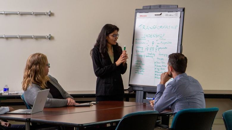 A businesswoman presents about transformative leadership to two colleagues