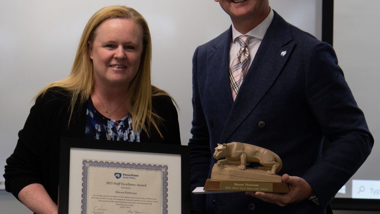Chancellor presents a staff member with an awards plaque and lion shrine