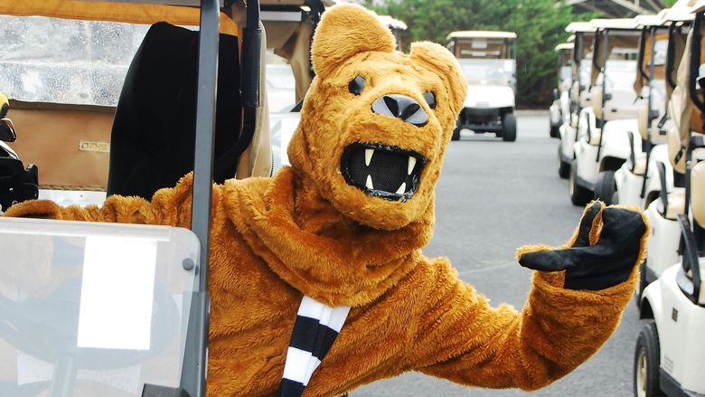 The Nittany Lion leans out of a golf cart and waves.
