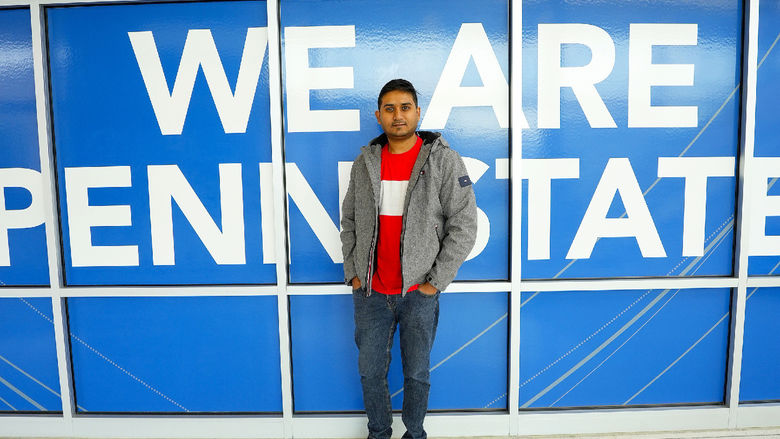 person standing in front of we are penn state sign