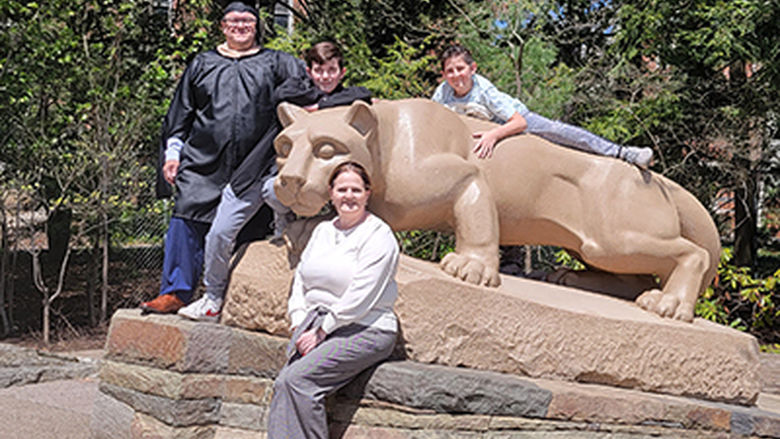 Two adults and two children pose in front of the Nittany Lion Shrine.
