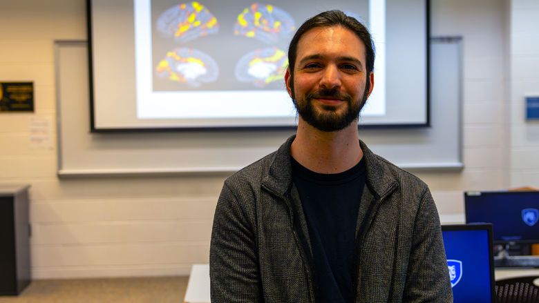 person in front of projector screen with brain imaging displayed