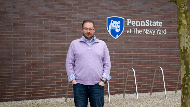 Todd Krout standing in front of the Penn State at the Navy Yard logo on Build 7R at the Navy Yard