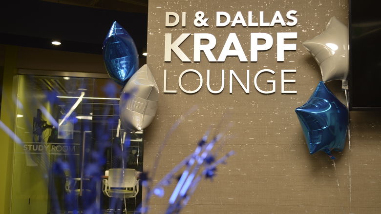 Sign for the Di & Dallas Krapf lounge framed by blue and silver balloons