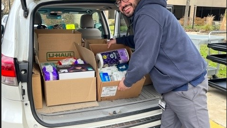 A man loads boxes of food and personal care items into a car