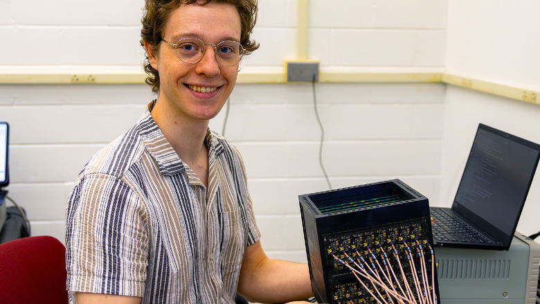 person at computer desk next to scientific device