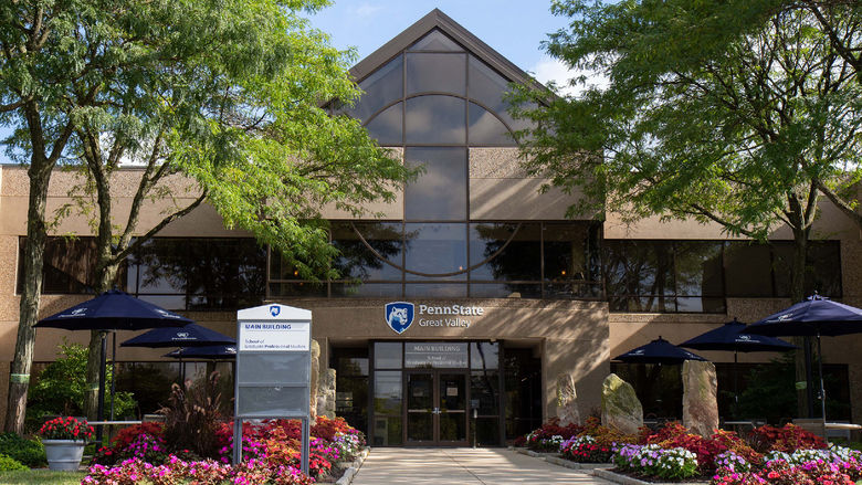 Photo of the exterior of Penn State Great Valley's Main Building, surrounded by trees and flowers