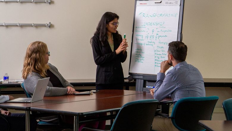 A businesswoman presents about transformative leadership to two colleagues