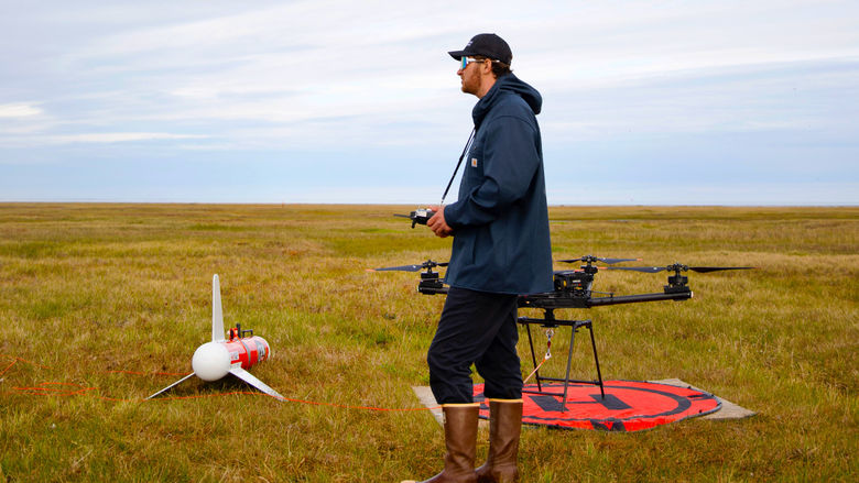 person standing next to drones in field