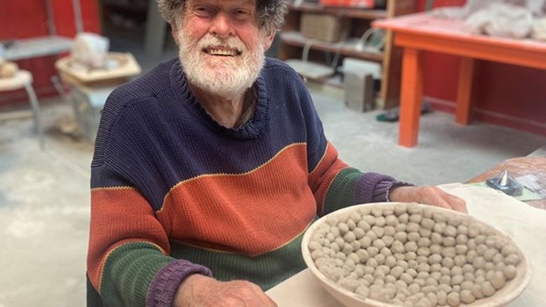 A man smiling by a ceramic bowl