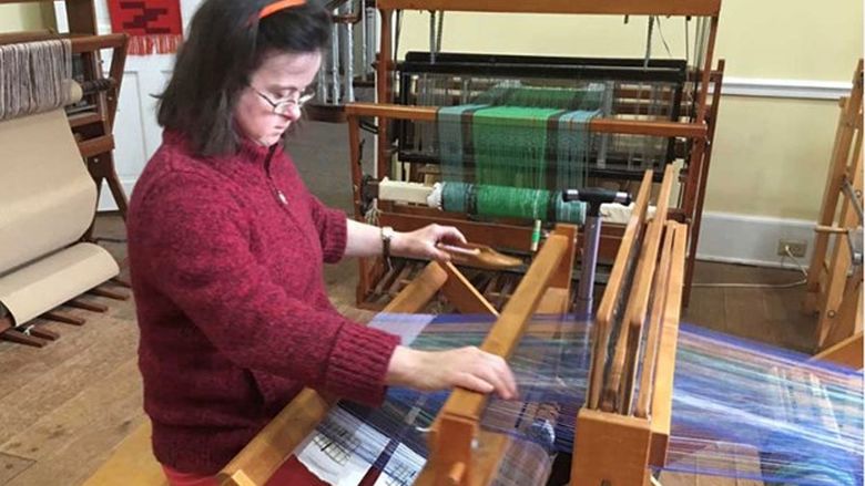 A woman working on a a project at a loom