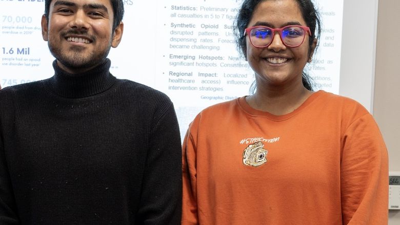 Data analytics students stand in front of their poster about a data-driven response to the opioid epidemic