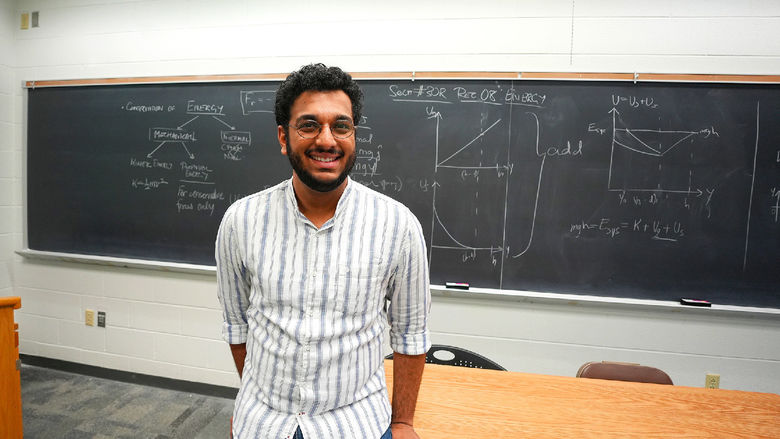 person standing in front of chalkboard with equations on it