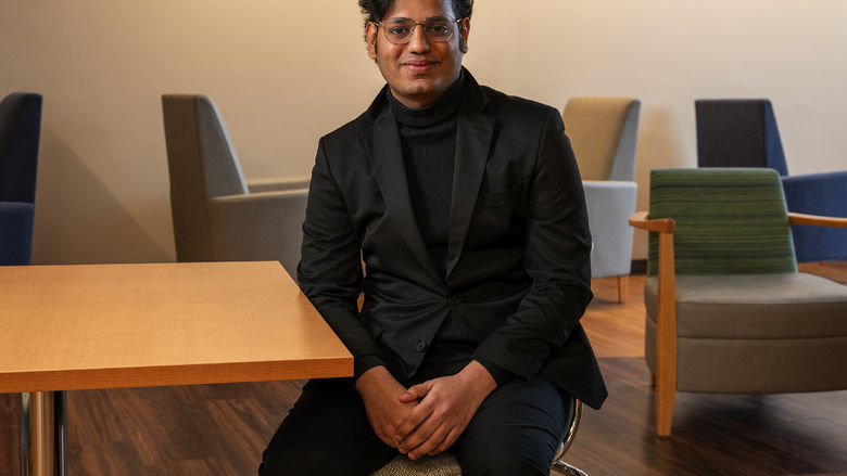 Data analytics graduate Rahul Vemuri sits at a table on Penn State Great Valley's campus