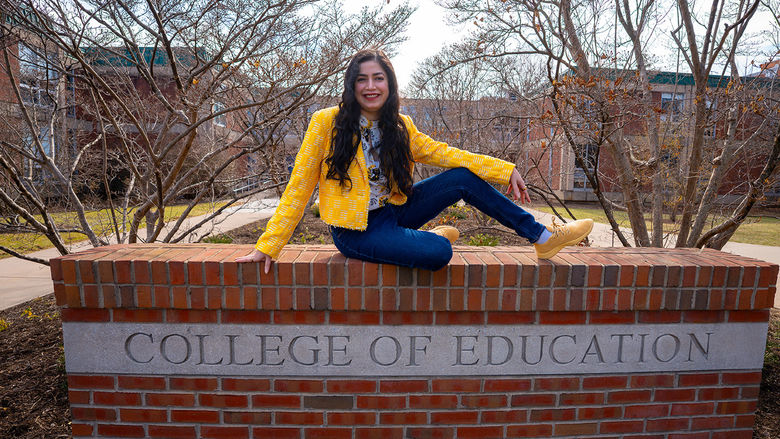 woman sitting on College of Education sign