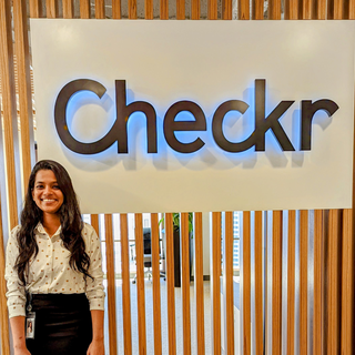 Namratha Sri Mateti standing in front of a wall with the Checkr logo