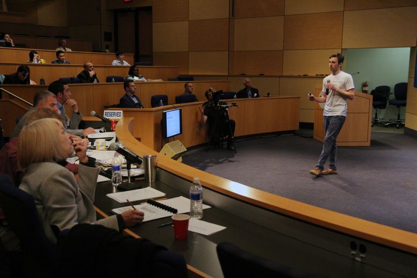 Student presenting business idea to panel of judges in auditorium