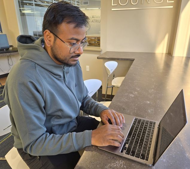 A student researcher works on his laptop