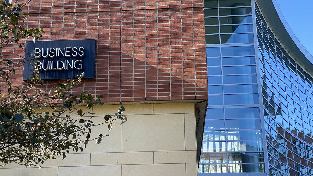 The sign for the Business Building is on a brick wall.