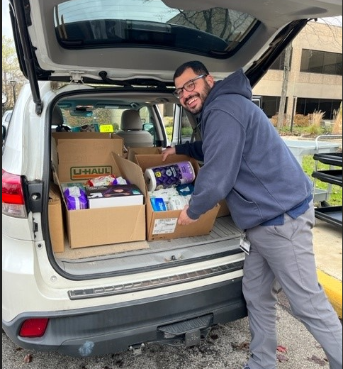 A man loads boxes of food and personal care items into a car